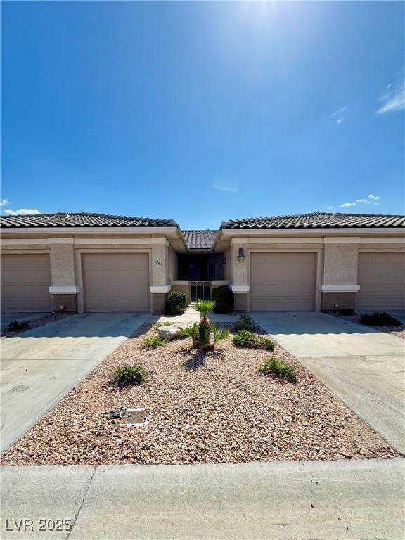 view of front of home featuring stucco siding, concrete driveway, a tiled roof, and a garage
