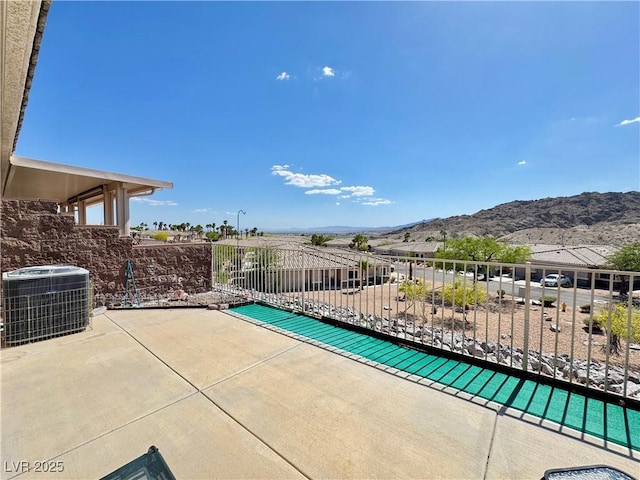 view of patio featuring central AC unit, a mountain view, and fence