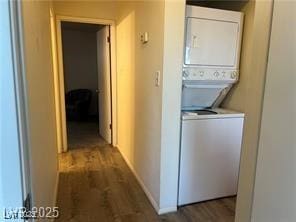 laundry area featuring wood finished floors, stacked washer and clothes dryer, and laundry area