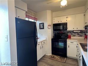 kitchen with light countertops, wood finished floors, a ceiling fan, black appliances, and white cabinetry