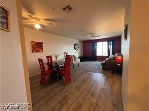 dining space with wood finished floors, a ceiling fan, and visible vents