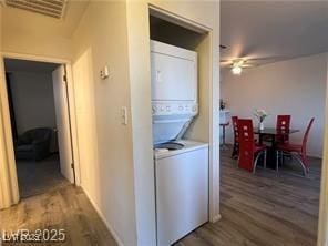 laundry room featuring wood finished floors, stacked washer and clothes dryer, laundry area, and ceiling fan