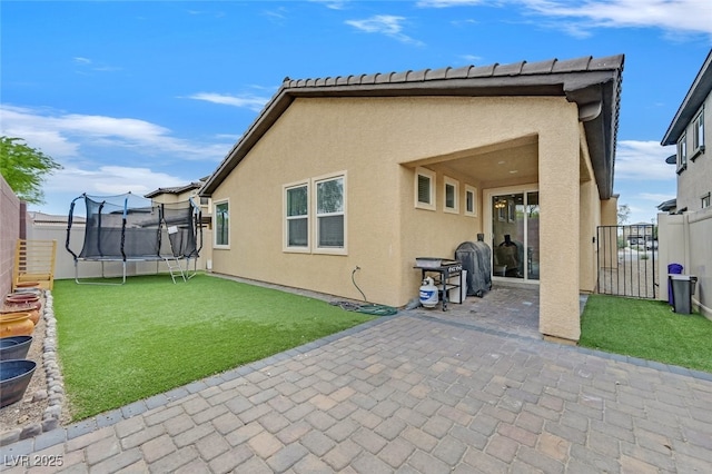 2104 Leatherbridge Ct, North Las Vegas, NV 89081 - back of property with a trampoline, a patio area, and stucco siding
