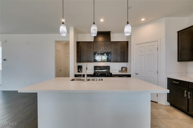 1004 Huckburn Ave, Henderson, NV 89015 - kitchen with a kitchen island with sink, a sink, dark brown cabinetry, light countertops, and black appliances