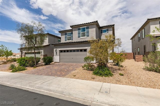 1004 Huckburn Ave, Henderson, NV 89015 - mediterranean / spanish-style home with stucco siding, an attached garage, a tiled roof, and decorative driveway