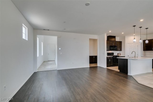 1004 Huckburn Ave, Henderson, NV 89015 - kitchen featuring black appliances, open floor plan, light wood-type flooring, dark brown cabinetry, and light countertops