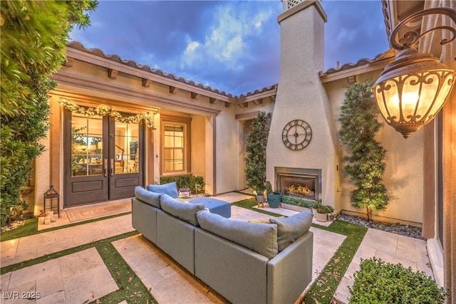 view of patio with an outdoor living space with a fireplace and french doors
