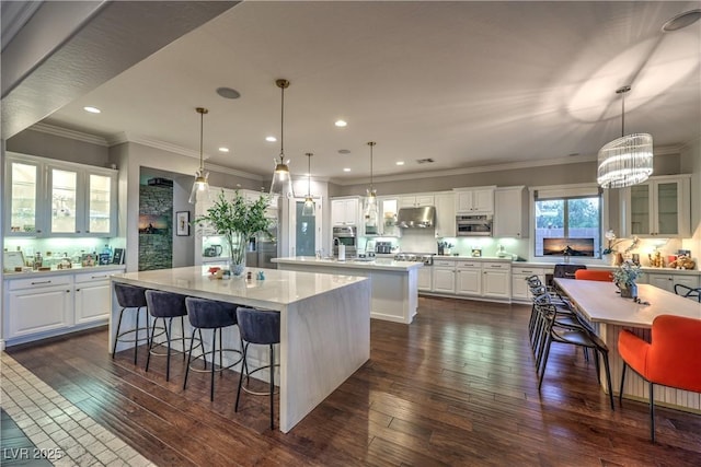 kitchen featuring under cabinet range hood, light countertops, dark wood-type flooring, a center island, and glass insert cabinets