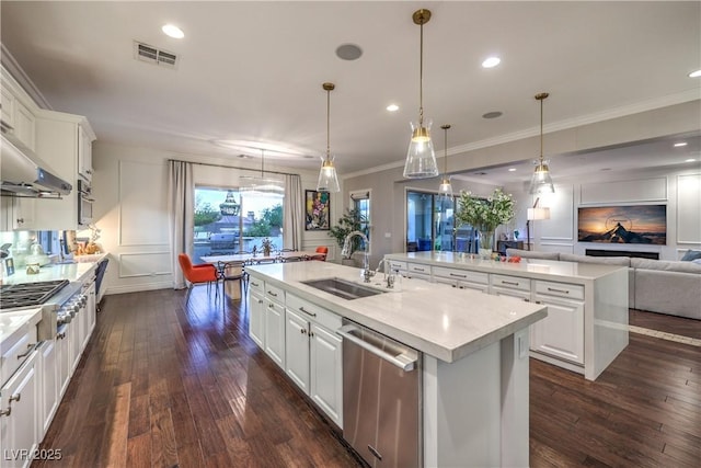kitchen featuring stainless steel appliances, a sink, open floor plan, visible vents, and an island with sink