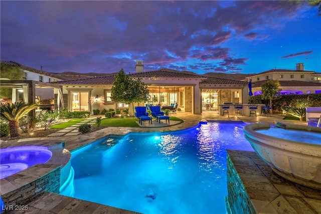 view of swimming pool featuring a patio area, outdoor dry bar, and a pool with connected hot tub