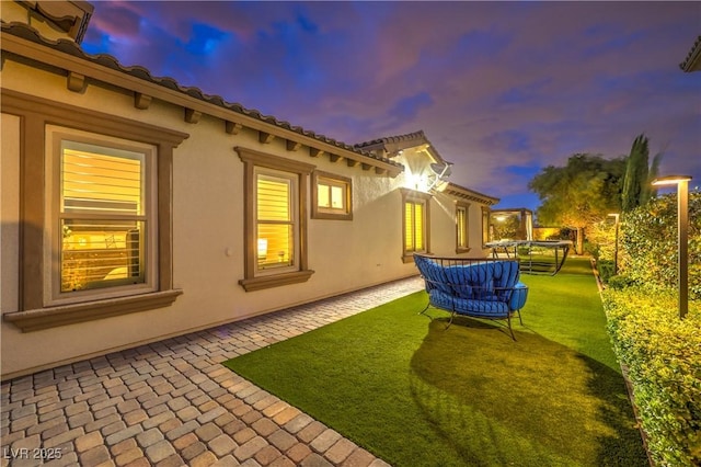 yard at dusk featuring a patio