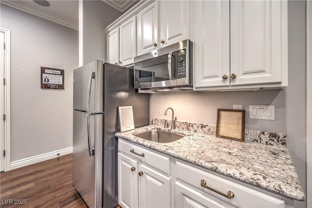 kitchen with dark wood-style floors, stainless steel appliances, a sink, crown molding, and white cabinetry