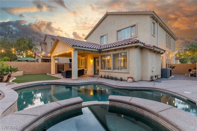 4573 Milvio Ave, Las Vegas, NV 89141 - back of house at dusk with stucco siding, a patio, a tile roof, a fenced backyard, and a pool with connected hot tub