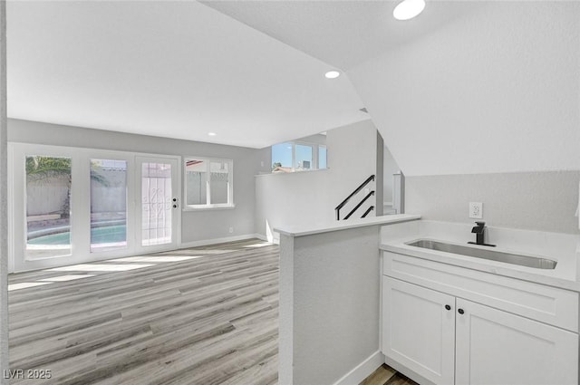 3791 El Camino Rd, Las Vegas, NV 89103 - kitchen featuring light wood-type flooring, white cabinets, light countertops, a peninsula, and plenty of natural light