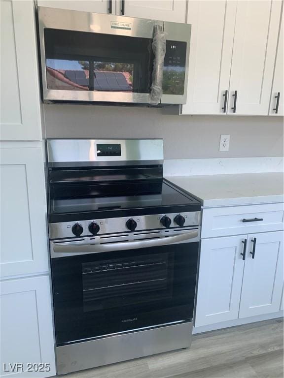 3791 El Camino Rd, Las Vegas, NV 89103 - kitchen with appliances with stainless steel finishes, white cabinetry, light countertops, and light wood-type flooring