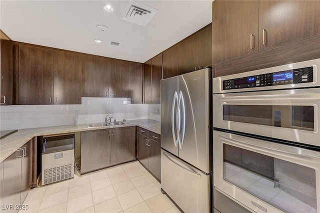 kitchen with dark brown cabinetry, appliances with stainless steel finishes, a sink, and visible vents