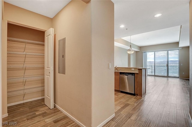 corridor with electric panel, wood finished floors, a sink, baseboards, and recessed lighting
