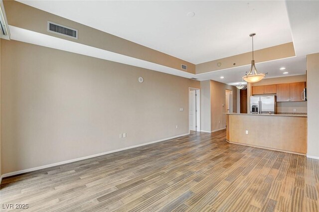 unfurnished living room with baseboards, light wood finished floors, recessed lighting, and visible vents