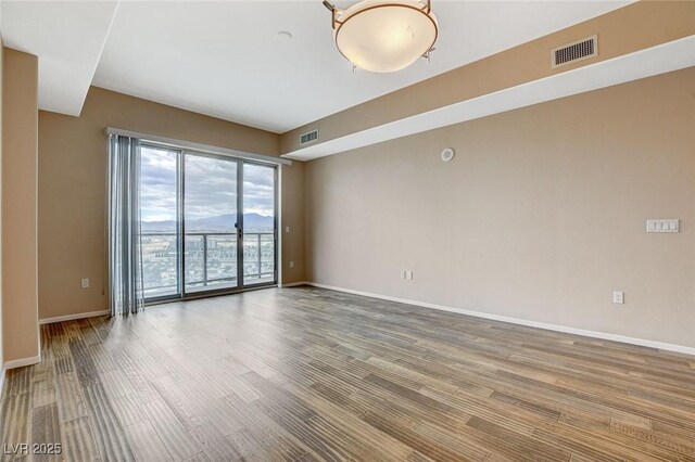 spare room with visible vents, baseboards, and wood finished floors