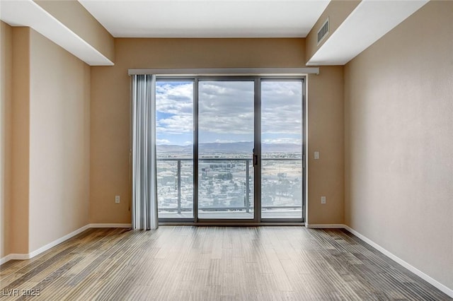 spare room featuring baseboards, wood finished floors, and visible vents