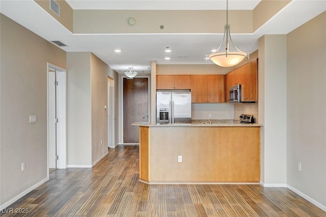 kitchen featuring visible vents, appliances with stainless steel finishes, wood finished floors, baseboards, and a peninsula