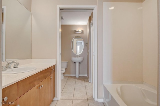 full bathroom featuring a sink, tile patterned flooring, toilet, a bathtub, and baseboards