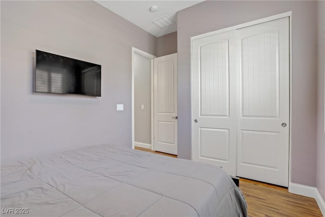 bedroom with wood finished floors, a closet, and baseboards
