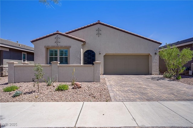 mediterranean / spanish-style house featuring stucco siding, an attached garage, decorative driveway, and fence private yard