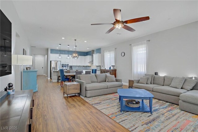 living area with recessed lighting, light wood-type flooring, a ceiling fan, and baseboards