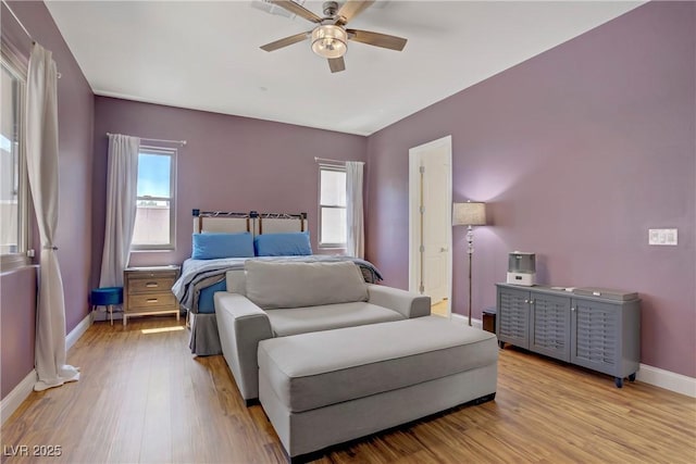 bedroom with light wood-style floors, a ceiling fan, and baseboards