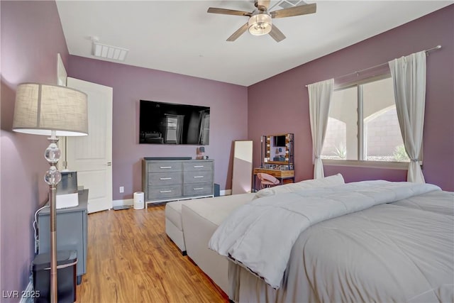 bedroom with baseboards, visible vents, light wood-style floors, and ceiling fan