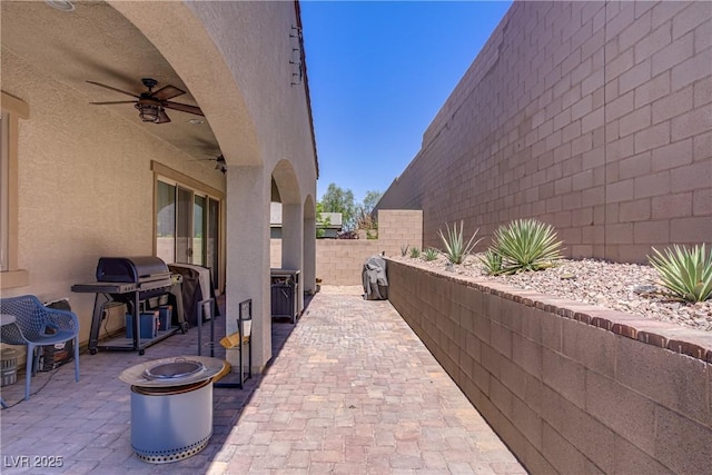 view of patio with a ceiling fan, area for grilling, a fenced backyard, and an outdoor fire pit