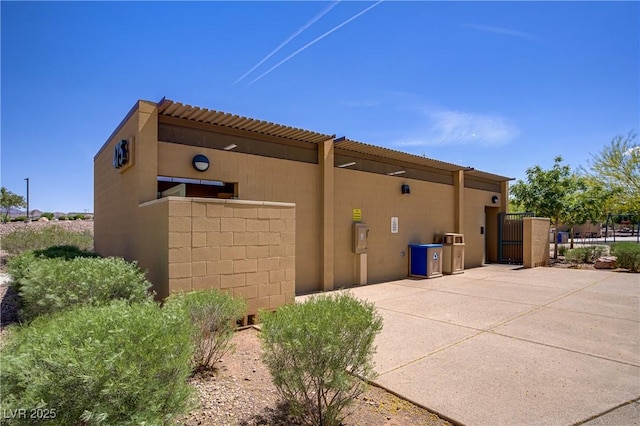 view of property exterior with stucco siding, a gate, and fence