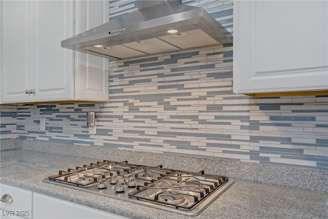 kitchen with stainless steel gas stovetop, extractor fan, white cabinets, and decorative backsplash