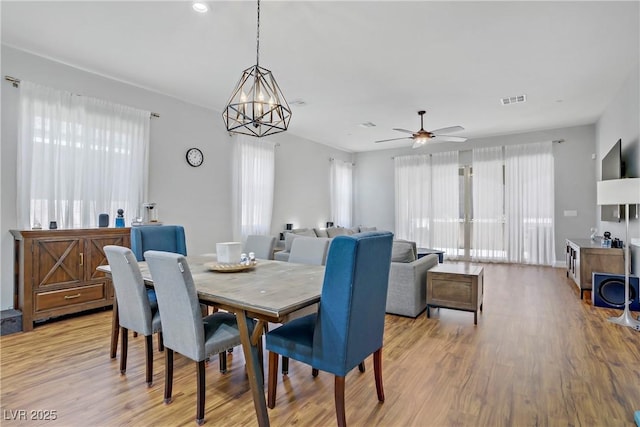 dining room with ceiling fan with notable chandelier, visible vents, and light wood-type flooring