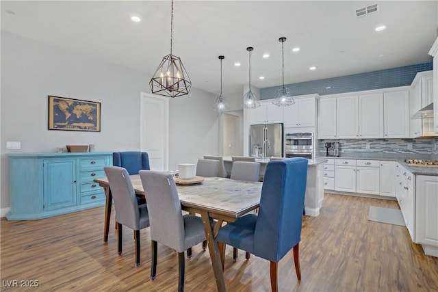 dining space featuring an inviting chandelier, wood finished floors, visible vents, and recessed lighting