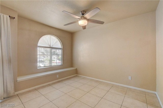 unfurnished room featuring baseboards, light tile patterned floors, and ceiling fan