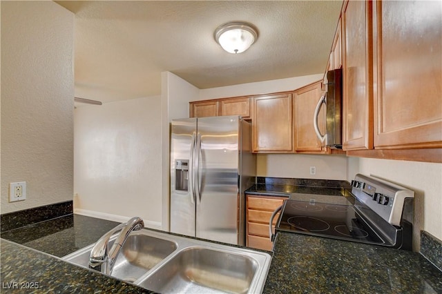 kitchen with dark stone countertops, appliances with stainless steel finishes, and a sink