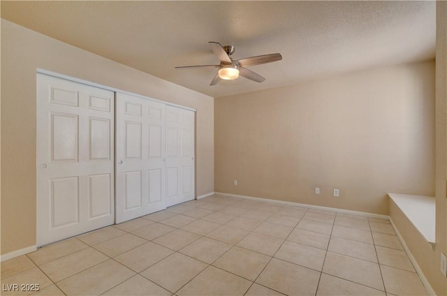 unfurnished bedroom featuring light tile patterned floors, ceiling fan, baseboards, and a closet