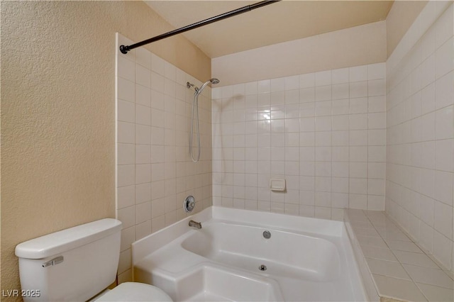 bathroom featuring toilet, shower / bathtub combination, and a textured wall