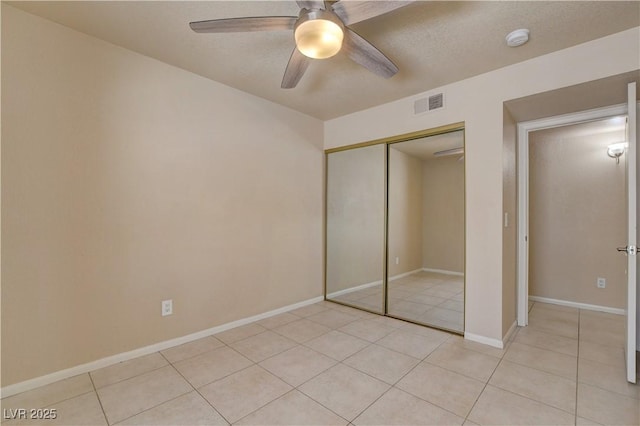 unfurnished bedroom featuring light tile patterned floors, a closet, ceiling fan, visible vents, and baseboards