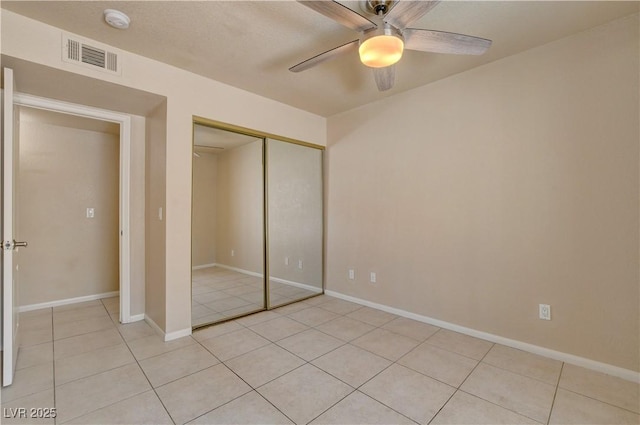 unfurnished bedroom with light tile patterned floors, visible vents, baseboards, a closet, and a ceiling fan
