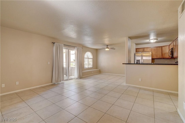 unfurnished living room featuring light tile patterned flooring, a ceiling fan, visible vents, and baseboards