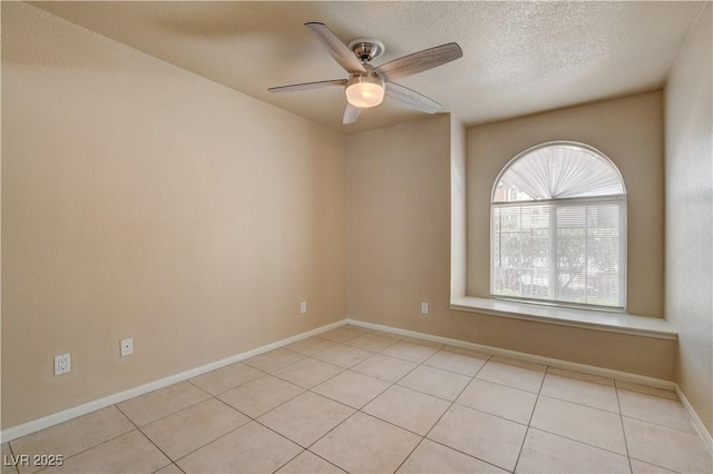 empty room with baseboards, light tile patterned floors, ceiling fan, and a textured ceiling