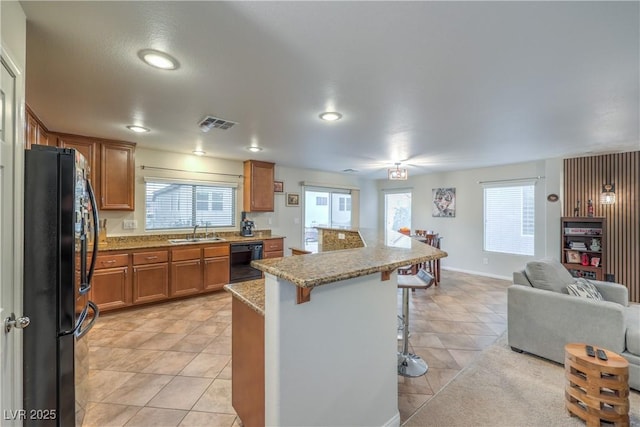 6546 American Flower St, Las Vegas, NV 89148 - kitchen with black appliances, a sink, open floor plan, a kitchen bar, and brown cabinets