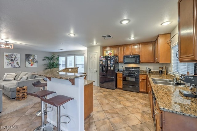 6546 American Flower St, Las Vegas, NV 89148 - kitchen with black appliances, a sink, a breakfast bar, brown cabinets, and open floor plan
