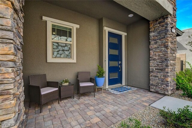 897 Woodburn Ln, Las Vegas, NV 89138 - doorway to property with stucco siding, stone siding, and a patio area