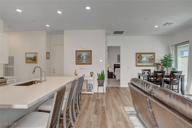 897 Woodburn Ln, Las Vegas, NV 89138 - kitchen with light wood finished floors, light countertops, a breakfast bar area, recessed lighting, and white cabinets