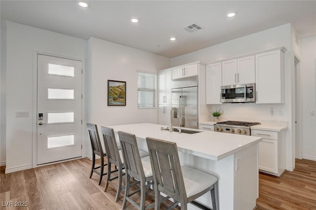 897 Woodburn Ln, Las Vegas, NV 89138 - kitchen featuring stainless steel appliances, a center island with sink, light wood-type flooring, white cabinets, and recessed lighting