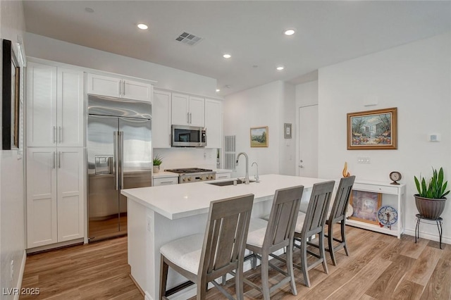 897 Woodburn Ln, Las Vegas, NV 89138 - kitchen with stainless steel appliances, light wood-type flooring, a breakfast bar, white cabinets, and recessed lighting